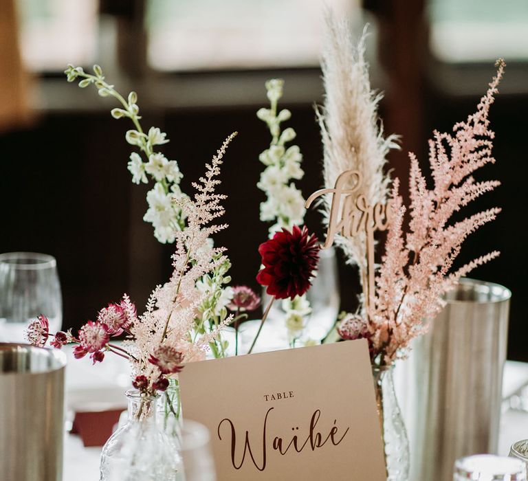 Classic wedding table sign on wooden holder with small floral arrangements to make a table centrepiece 