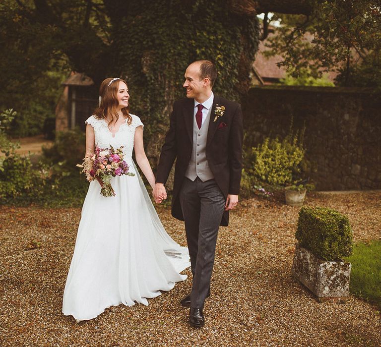 Bride in traditional lace gown with groom in a three piece morning suit at their wedding 