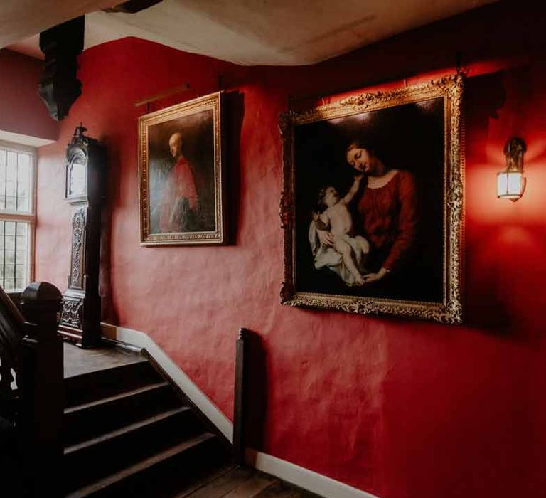 Interior of Elmore Court Gloucestershire with red walls, gold framed portraits and large grandfather clock 