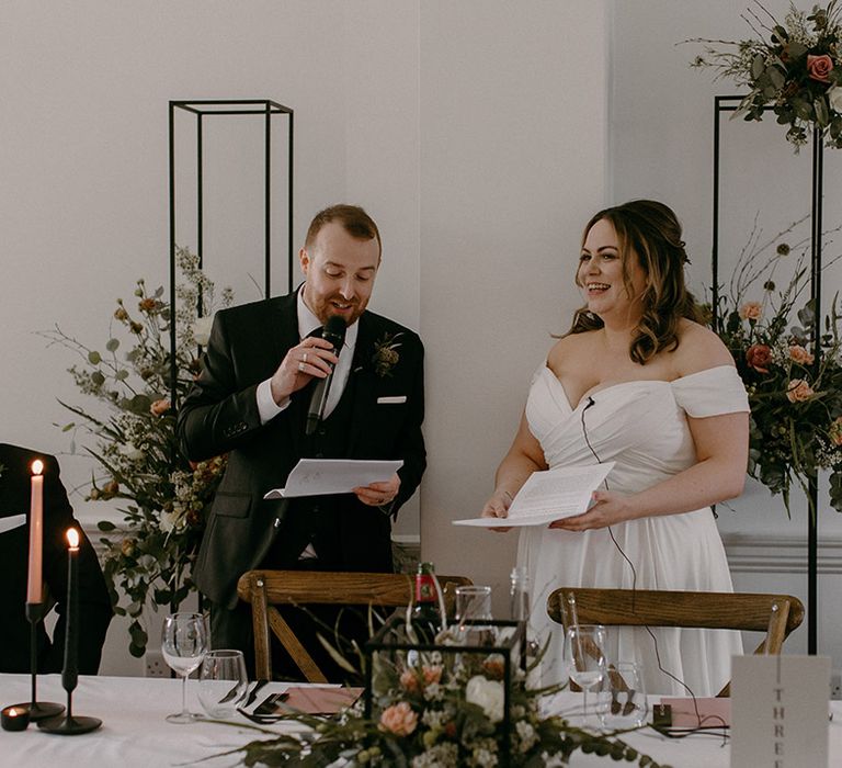 The bride and groom stand up together with microphones for their joint wedding speech 