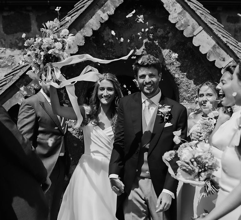 church confetti exit with bride in a Suzanne Neville princess wedding dress and groom in a morning suit 