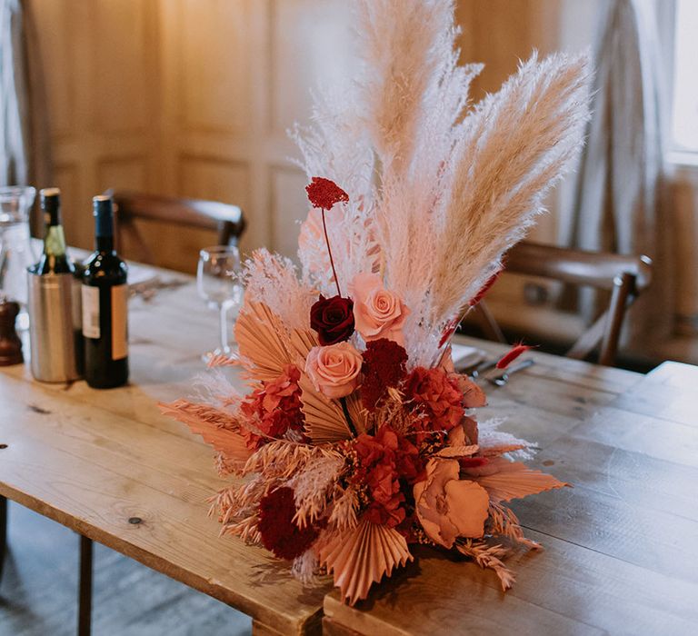 Preserved wedding flower arrangement with pink and red roses, pampas grass and dried palm leaves 