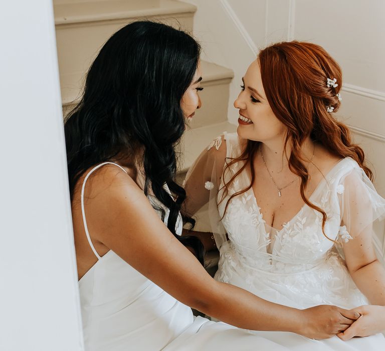 Bride in satin slip wedding dress with bride in tulle floral wedding dress at same sex lesbian wedding 