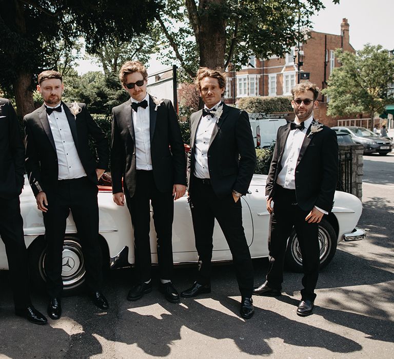 Groom and groomsmen in black tuxedos with boho dried flower wedding buttonholes 