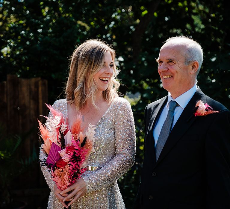 Bride wearing sparkling bespoke wedding dress with groom holding hot pink dried flower wedding bouquet 