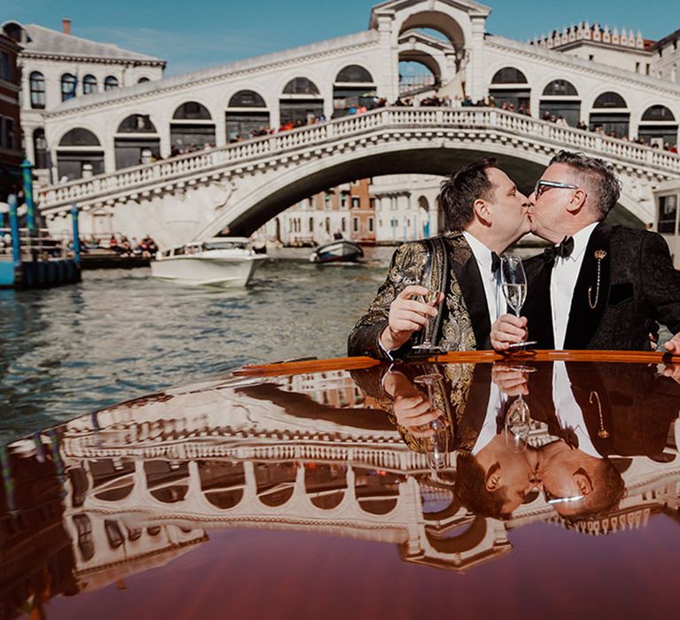 Two grooms riding on wedding boat at destination wedding in Venice 