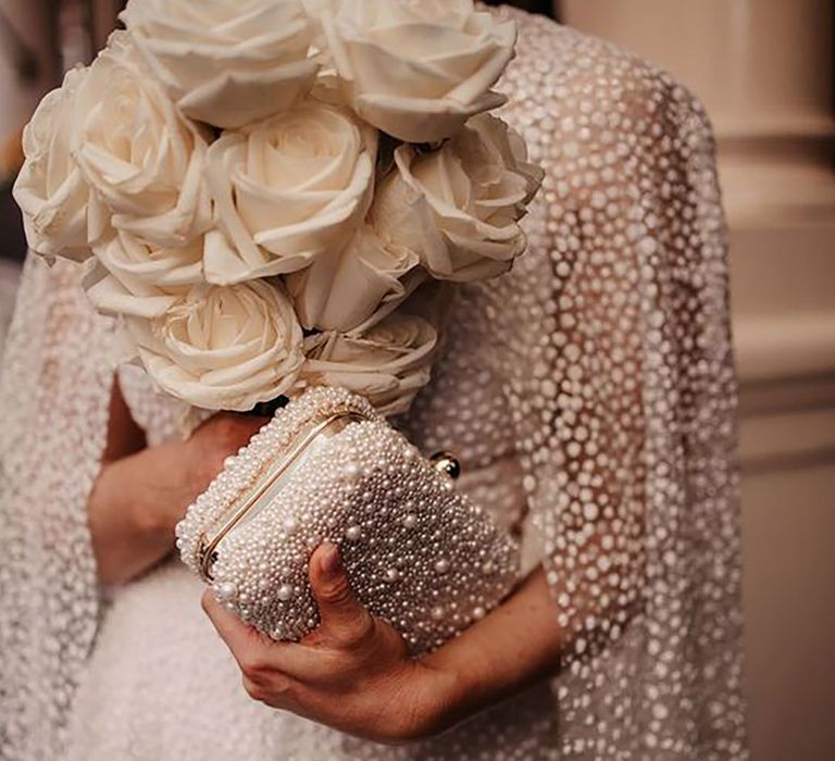 Bride holding a bridal pearl clutch and bouquet of wedding flowers by Emily Rose Photography