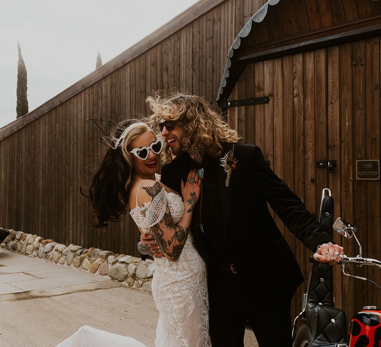 Groom in cowboy Western attire leaning into kiss the bride in a traditional lace wedding dress 