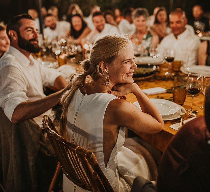 Bride with fishtail braid smiling during the festoon lit reception 