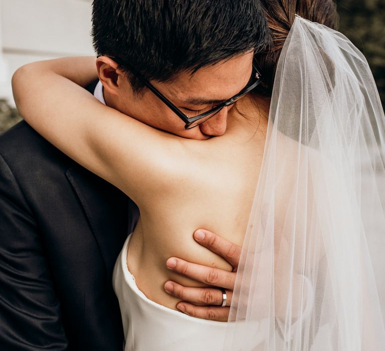 Intimate wedding portrait of the groom embracing his bride 