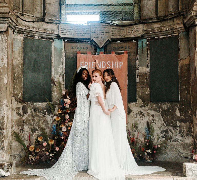 Brides in different casual wedding dresses embracing at the altar 