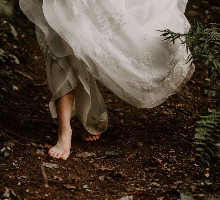 Bride walks barefoot through the forest in the Scottish Highlands with beaded floral wedding dress