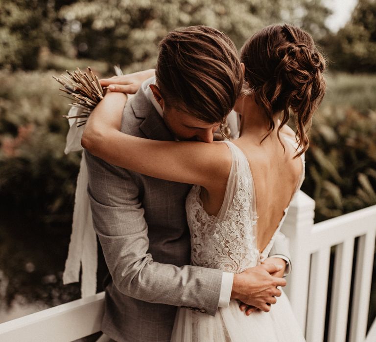 Bride in backless Watters wedding dress embraces groom