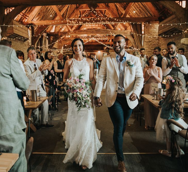 Bride and groom enter the wedding breakfast. Bride wears Christina Wu dress.