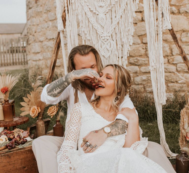 Bride & groom sit outside for outdoor picnic 