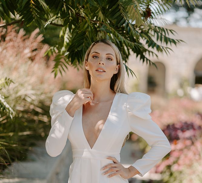 Bridesmaid with long blonde hair wearing a wide leg jumpsuit with long sleeves and plunging neckline. 