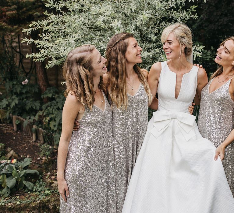 Bridal party portrait with bridesmaids in silver sequin dresses and bride in a classic wedding dress with bow detail