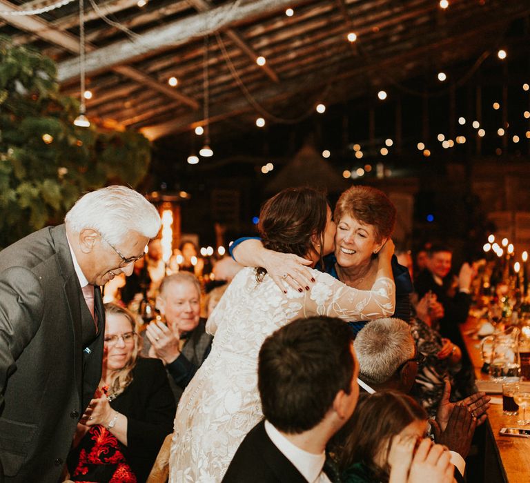 Bride in a lace Hermione de Paula wedding dress with long sleeves and button back kissing a guests at the wedding breakfast 