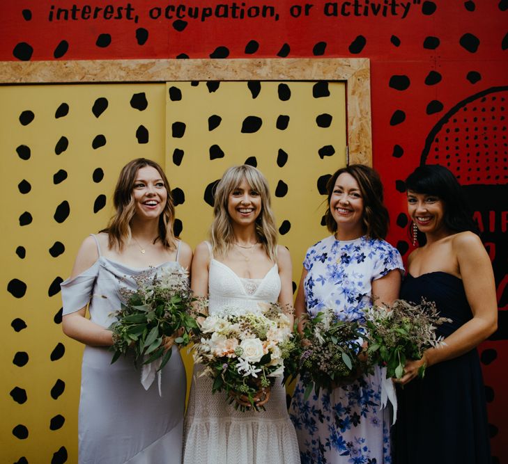 Portrait of bride and three bridesmaids holding bouquets. Bridesmaids wearing different dresses.