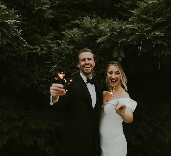 Bride & groom play with sparklers and laugh