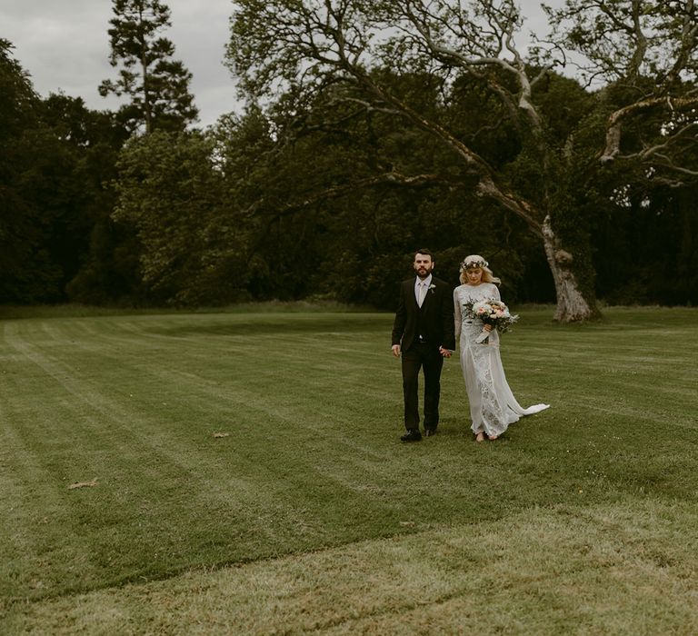 Bride in Grace Loves Lace wedding dress and single tier cathedral length veil walks with groom in black Hugo Boss suit at Drenagh Estate Wedding