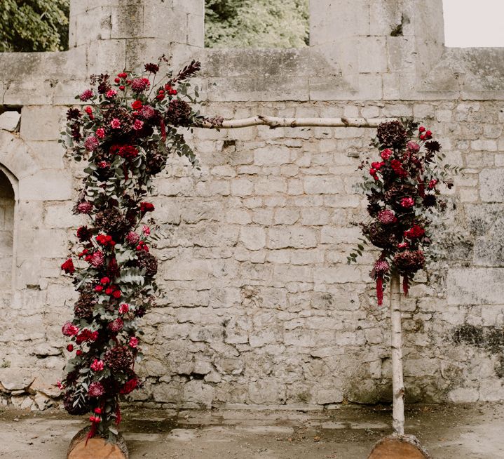 Drift wood wedding arch decorated with red wedding flowers 