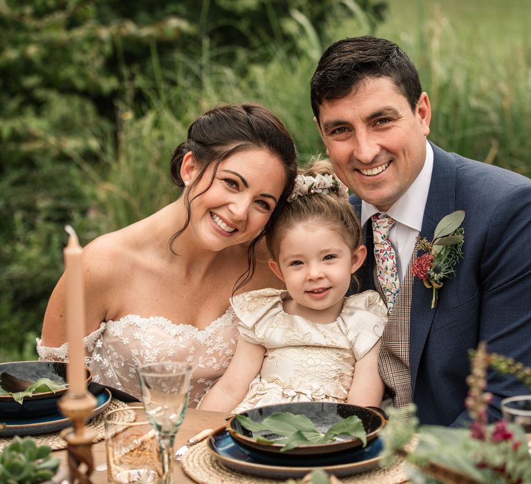 Bride & groom sit together with little during vow renewal dinner