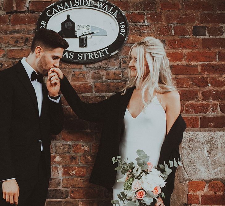 Groom in a black-tie suit kissing his brides hand at their Gas Street Church wedding 