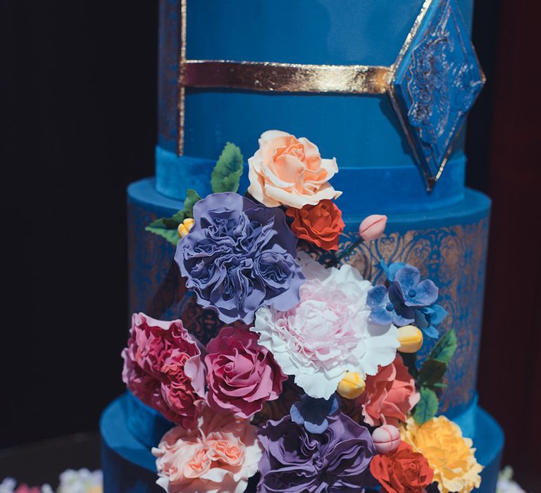 Blue wedding cake with brightly coloured floral decor