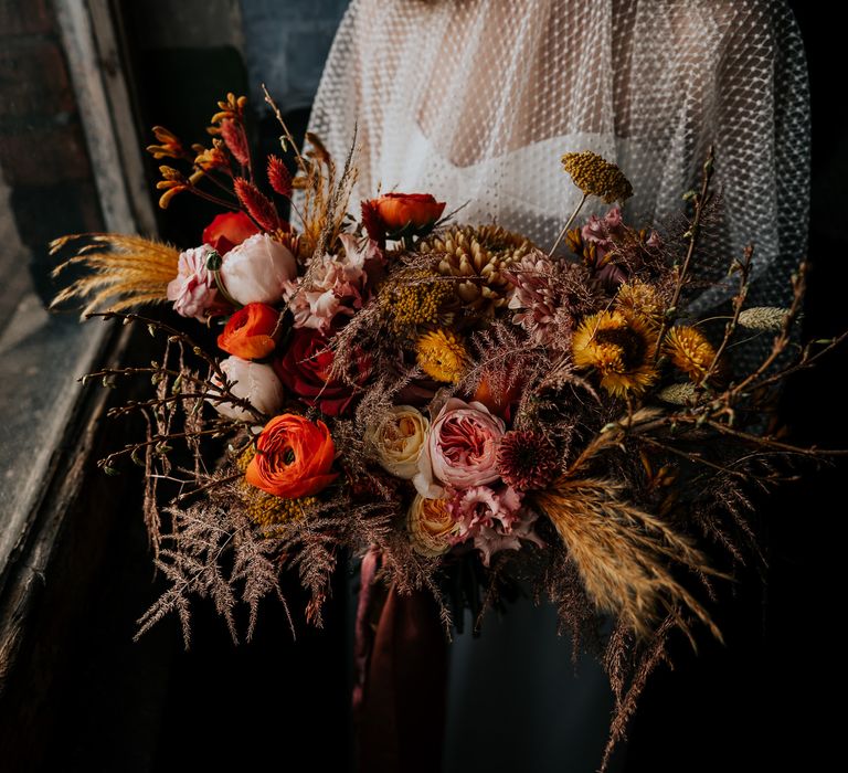 Dried and fresh flower autumn wedding bouquet in deep red, oranges and yellows