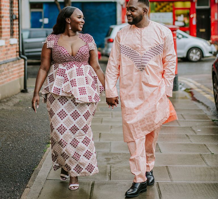 Bride & groom walk with one another in colourful outfits during wedding day