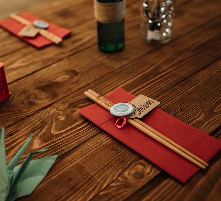 Rustic table setting with personalised engraved chopsticks on red napkins