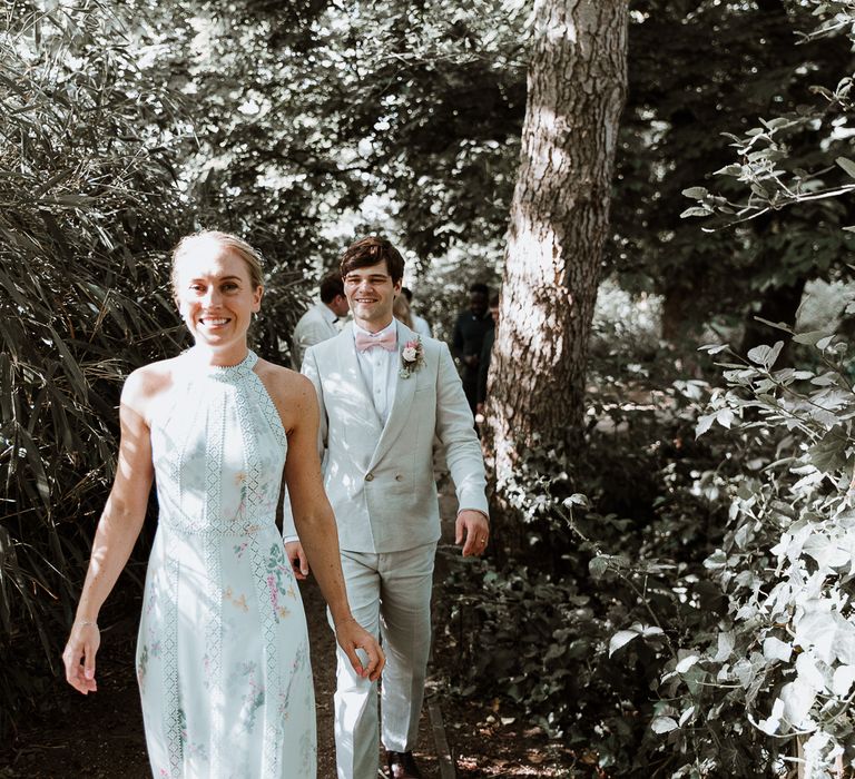 Bride & groom walk through woodlands on the day of their wedding