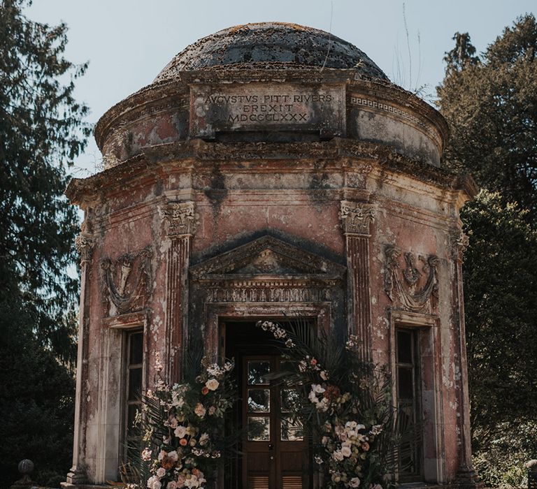 Larmer Tree wedding venue with outbuilding decorated in a muted flower arch 