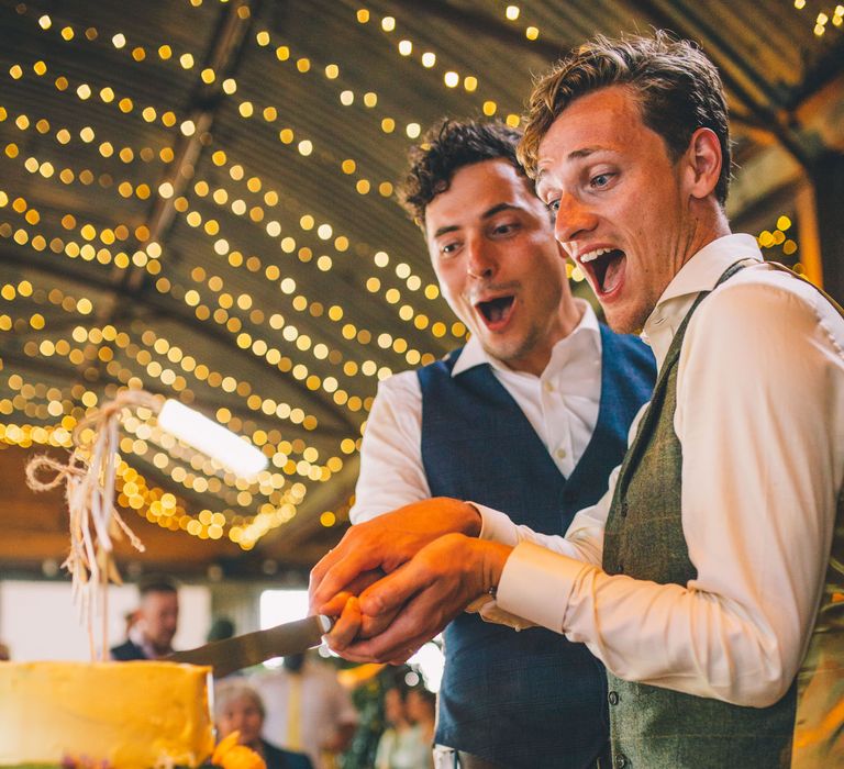 Grooms cut their wedding cake in barn on their wedding day | Story + Colour