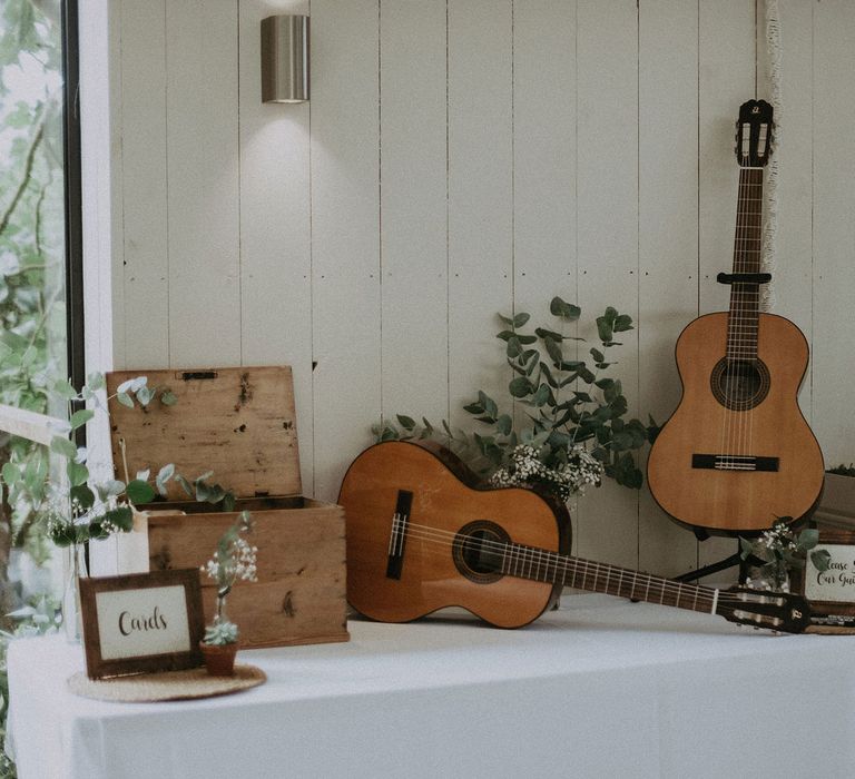 White table with card box, foliage decor and and guitar wedding guestbooks for Isle of Wight wedding with macrame wedding decor