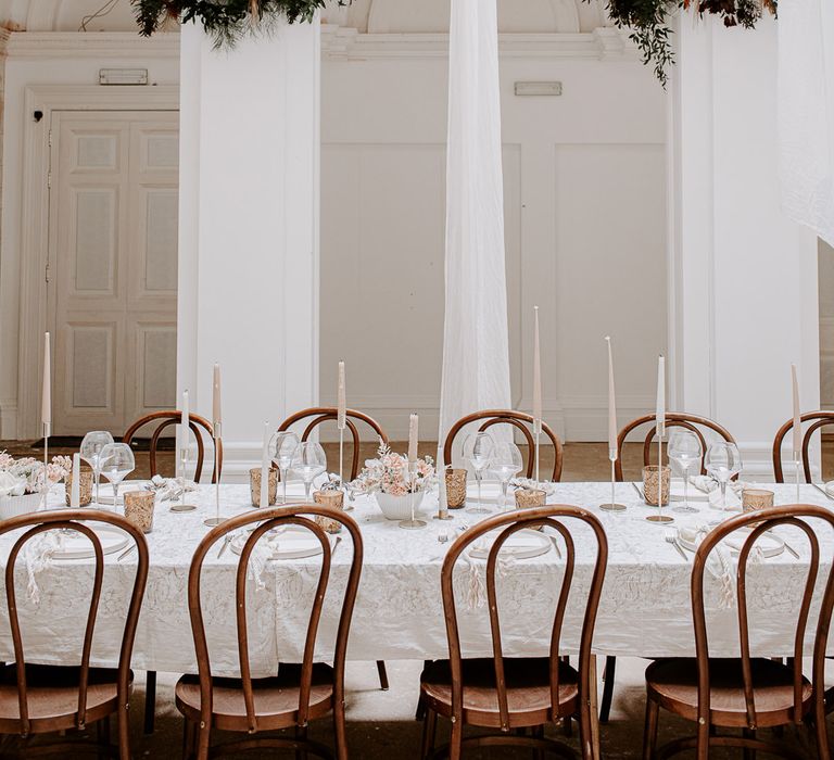 Minimalist wedding reception at Bylaugh Hall with drapes, candles and floral centrepieces