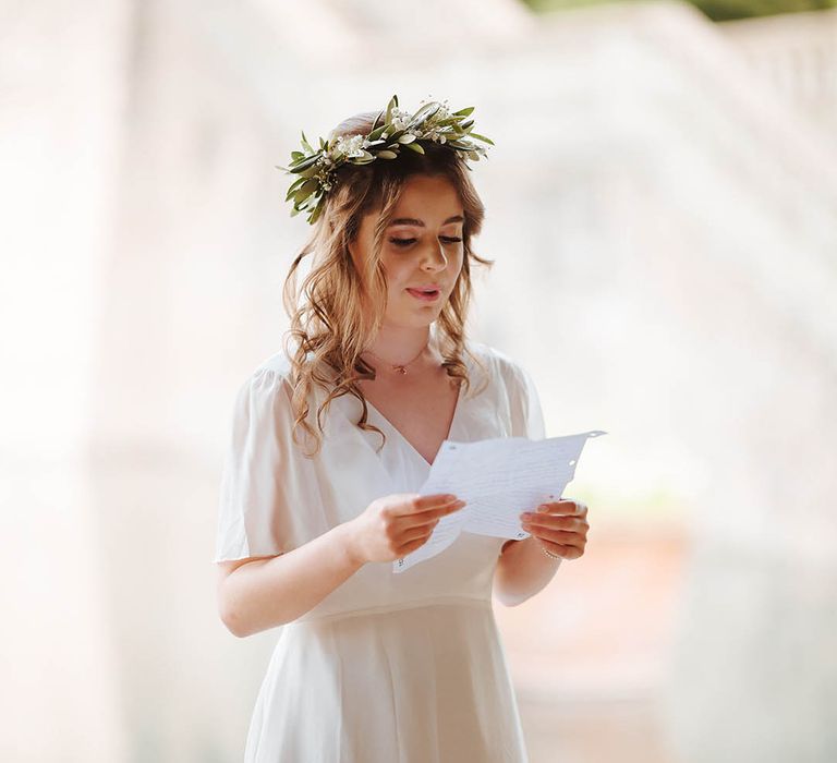 Bridesmaid reads during ceremony whilst wearing floral crown