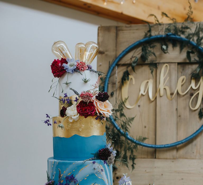 Bright blue and gold wedding cake with light bulb cake topper 