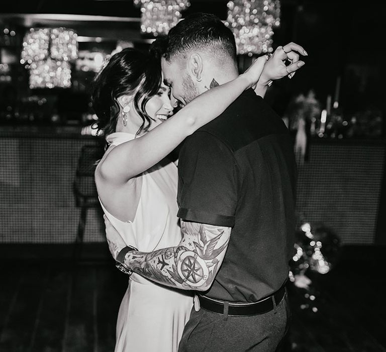 Black and white portrait of the bride and groom doing their first dance at their city bar wedding 