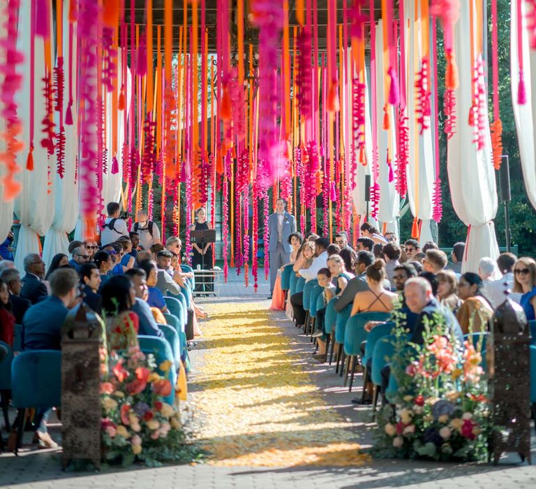 Beautifully bright hangings suspend from ceiling for hot pink and orange wedding ceremony in Lake Garda