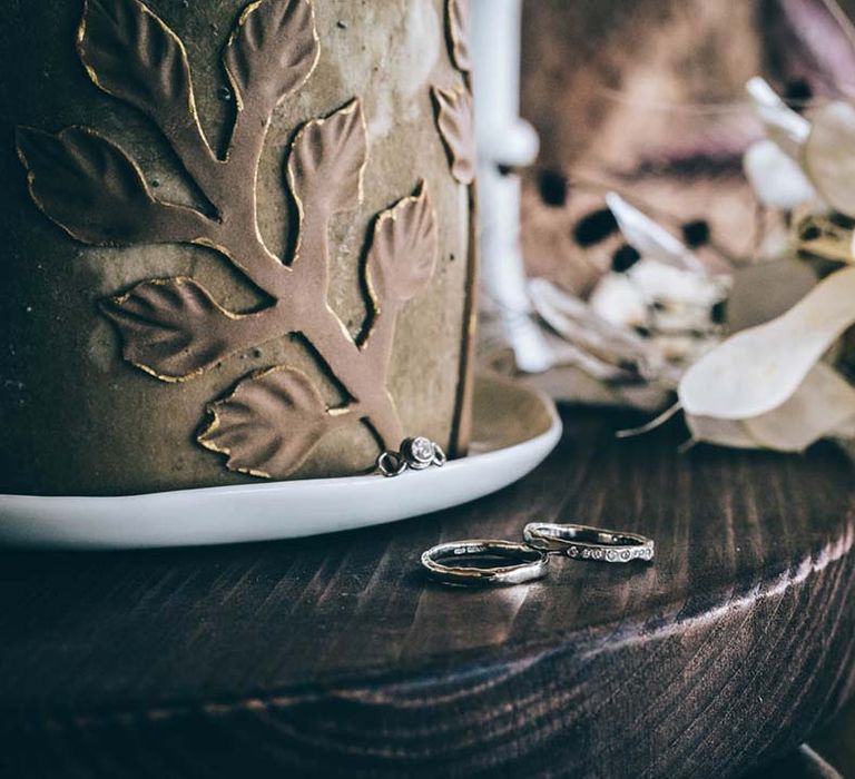 diamond wedding bands and engagement ring resting on the cake table 