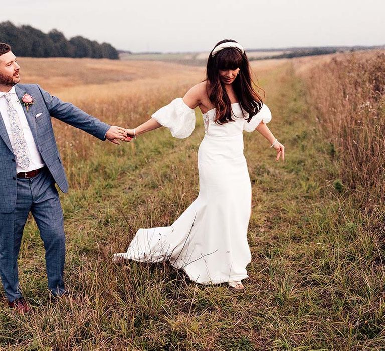 Bride & groom walk along fields in the countryside on their wedding day