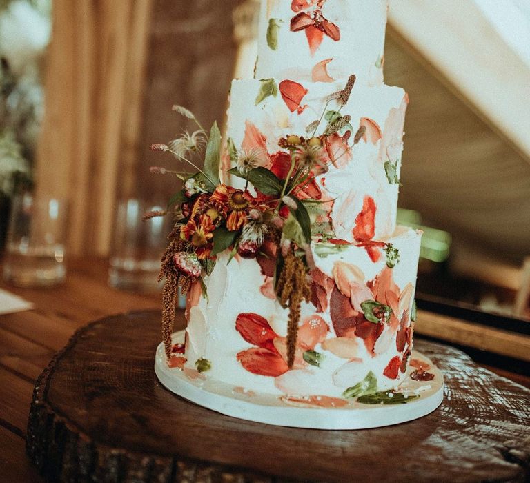 Autumnal three-tier cake complete with deep red and orange colours and white frosting 