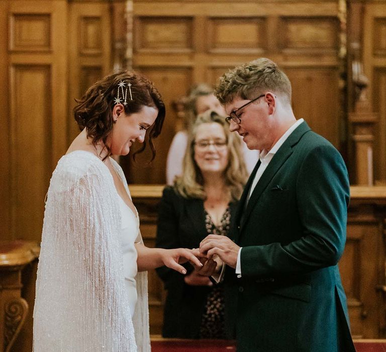 Groom places ring on his brides finger during wedding ceremony