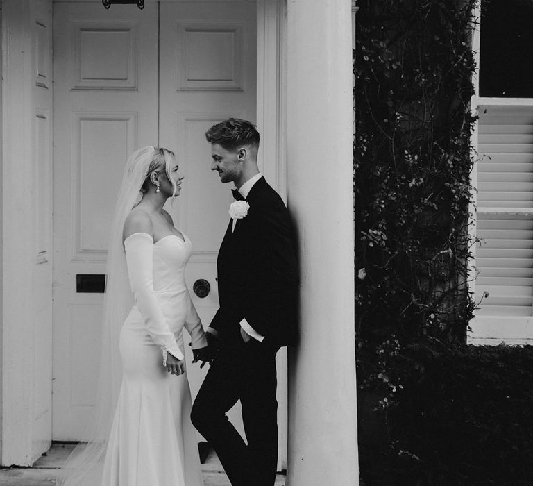 Black and white portrait of the bride and groom at Northbrook Park in a tuxedo and fitted wedding dress with detachable long sleeves 