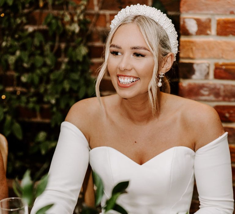 Beautiful bride with natural makeup wearing a pearl headband and strapless wedding dress with detachable long sleeves 