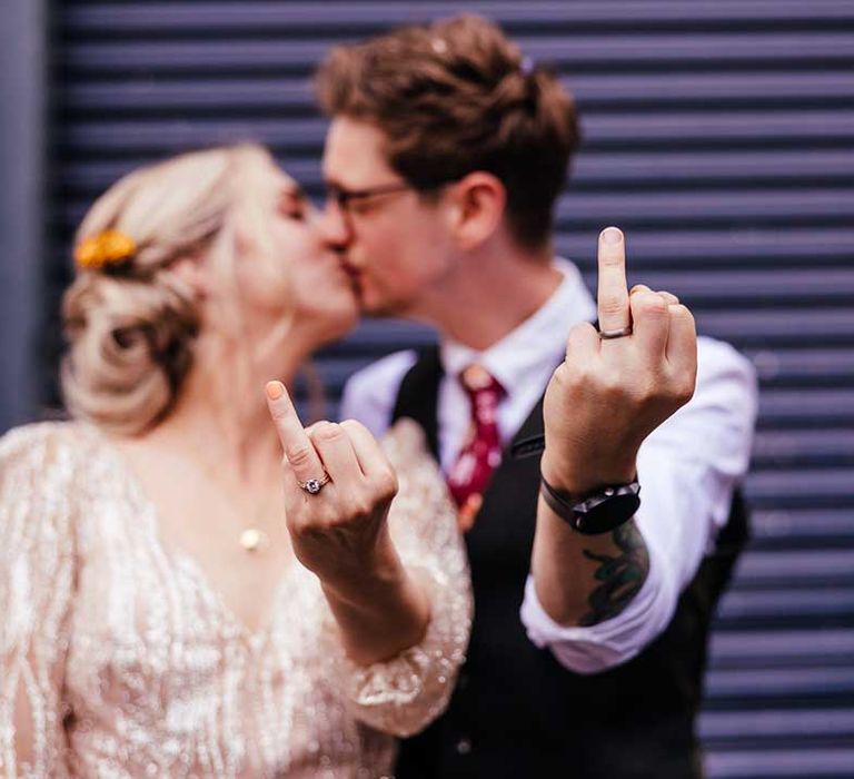 Bride & groom flash their wedding rings on their wedding day as they kiss