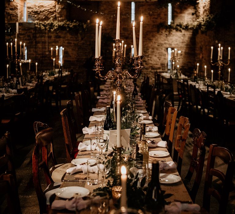 Stone barn wedding reception at Lyde court decorated with candelabras and taper candles 