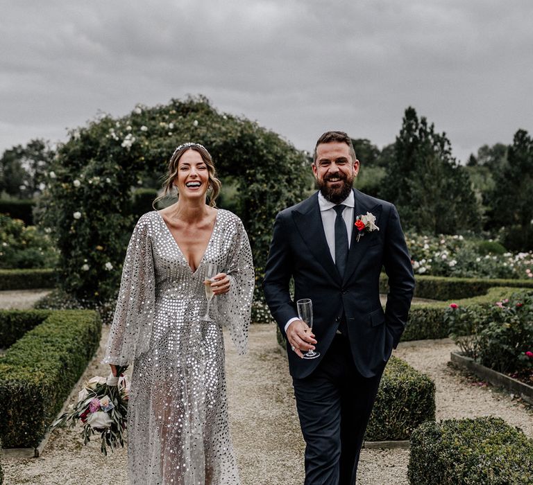 back garden wedding with bride in a silver sequin wedding dress and bridal crown, and groom in a navy suit 